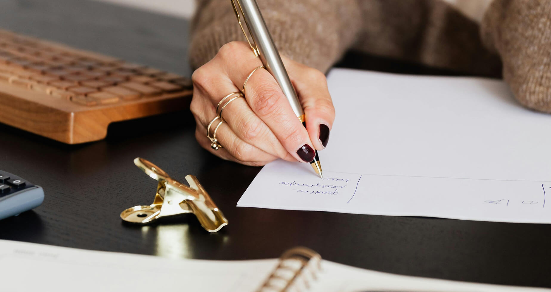 Hand hält Kugelschreiber und schreibt auf einem Blatt Papier
